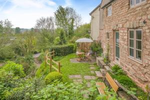 a garden with benches and a table and an umbrella at Tump Cottage in Walford +16 photos