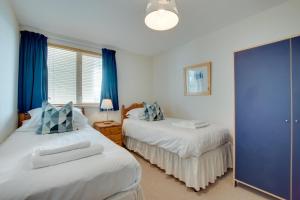 Dos camas en un dormitorio con cortinas azules. en Flat 31 Clifton Court, en Croyde
