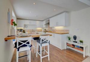 a kitchen with white cabinets and bar stools at Lobsters Loft in Appledore