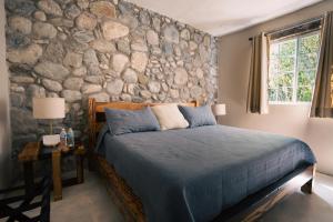 ein Schlafzimmer mit einer Steinwand und einem Bett in der Unterkunft Armadillo Mágico in Armadillo