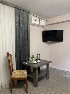 a dining room table with a chair and a television at Kifoyat Hotel in Samarkand