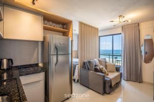 cocina con nevera de acero inoxidable y sofá en Hospédese a pasos de la playa de Itapuã, con piscina y gimnasio - RGF, en Salvador