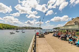 eine Gruppe von Menschen, die auf einem Pier neben dem Wasser sitzen in der Unterkunft Killas Cottage in Fowey + 10 Fotos