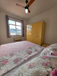 Schlafzimmer mit einem Bett, einem Fenster und einem Ventilator in der Unterkunft Apto no coração da Praia do Forte em Cabo Frio in Cabo Frio