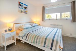 a white bedroom with a bed and a window at 23 Cae Du in Abersoch