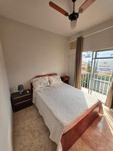 ein Schlafzimmer mit einem Bett und einem großen Fenster in der Unterkunft Apto no coração da Praia do Forte em Cabo Frio in Cabo Frio