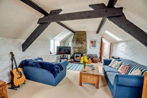 un soggiorno con un divano blu e una chitarra di Tyn Y Mur Cottage a Llangian
