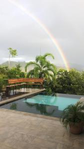 a rainbow over a swimming pool with a bench and a rainbow at Luxury In The Jungle in Barú