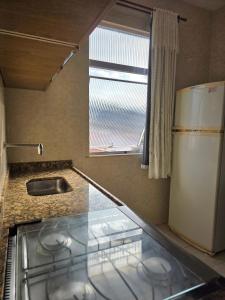 eine Küchentheke mit Spüle und Kühlschrank in der Unterkunft Apto no coração da Praia do Forte em Cabo Frio in Cabo Frio