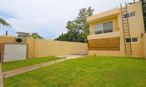 a large yellow house with a lawn in front of it at Departamentos VESA in Ajijic