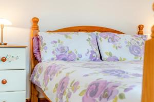 Cama con sábanas y almohadas de color púrpura y blanco en Tremill Lodge, en Wadebridge