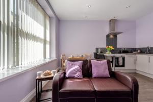 a living room with a brown leather couch and a kitchen at White Rose 1 in Tenby