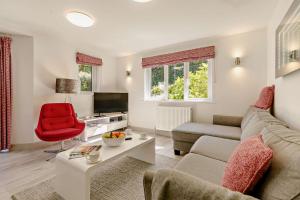 a living room with a couch and a red chair at Sennen - St Ives in Carbis Bay