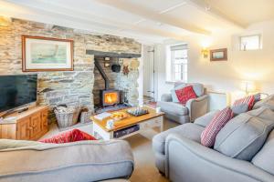 - un salon avec deux canapés et une cheminée en pierre dans l'établissement Popigale Cottage, à Helford