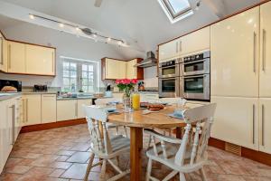 a kitchen with a wooden table and white chairs at Pearl Cottage - St Agnes in St. Agnes 