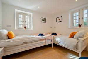 two beds in a room with two windows at Pearl Cottage - St Agnes in St. Agnes 