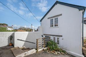 a white house with a fence in front of it at Pearl Cottage - St Agnes in St. Agnes 