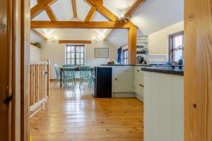 une cuisine avec parquet et une table avec des chaises dans l'établissement Coach House Cottage - Dorstone, à Dorstone