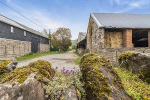 un bâtiment en pierre avec des fleurs devant une route dans l'établissement Coach House Cottage - Dorstone, à Dorstone