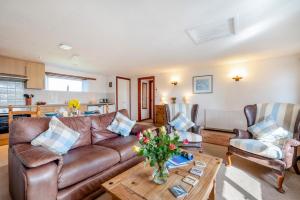 a living room with a brown leather couch and a table at Wren Cottage in St Merryn