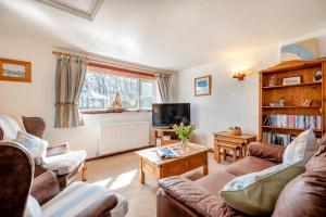 a living room with two couches and a tv at Wren Cottage in St Merryn