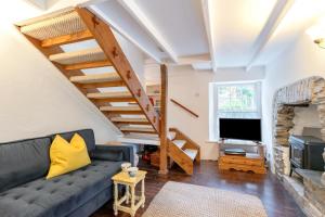 a living room with a couch and a tv at West Creek Cottage in Little Petherick