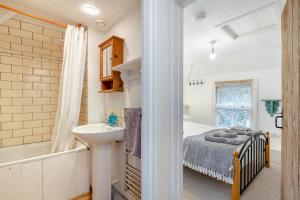 a bedroom with a bed and a sink and a tub at West Creek Cottage in Little Petherick