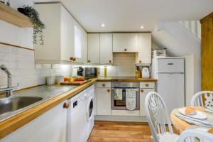 a kitchen with white cabinets and a sink and a table at The Cottage - Vineyard Street in Winchcombe +8 photos