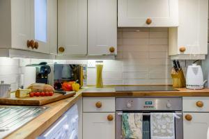 a kitchen with white cabinets and a counter top at The Cottage - Vineyard Street in Winchcombe
