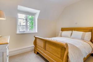 a bedroom with a wooden bed and a window at The Cottage - Vineyard Street in Winchcombe