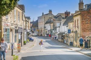 a woman crossing a street in a small town at The Cottage - Vineyard Street in Winchcombe