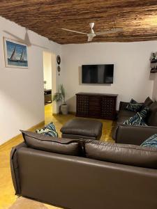 a living room with a leather couch and a flat screen tv at Beach Villa by Liv Zanzibar in Paje