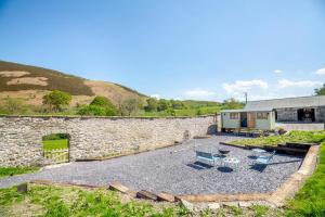 a stone building with a stone wall and a patio at Plas Uchaf Farm Retreat in Llannefydd