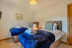 une chambre avec deux lits avec des couvertures bleues dans l'établissement Lavender Cottage - Brockenhurst, à Brockenhurst