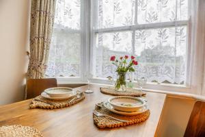 a dining room table with plates and a vase of flowers at Trem Y Fam in Llanfairfechan