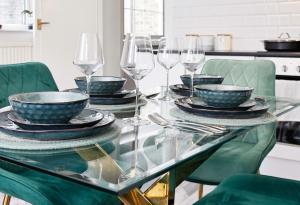 a glass table with plates and wine glasses on it at 3-Bed Cottage Sleeps 8 Walk to Thames Garden in Hampton