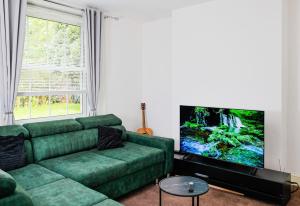 a living room with a green couch and a flat screen tv at 3-Bed Cottage Sleeps 8 Walk to Thames Garden in Hampton