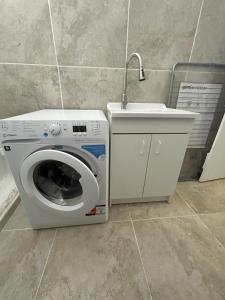 eine Waschmaschine und ein Waschbecken im Bad in der Unterkunft Bel appart moderne et climatisé "PAUL" in Alès