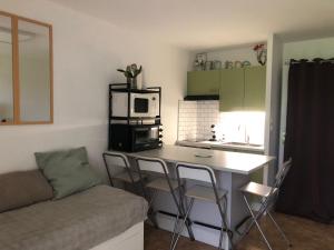 Una cocina con mesa y sillas y un microondas. en Studio cosy avec terrasse & vue sur pistes, en Gérardmer