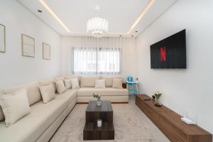 a living room with a white couch and a tv at LUXURY Apartment - IPTV - AC - Easy Parking - Cosy stay in Tangier