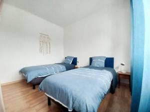 two beds in a room with blue sheets at L'Escapade Carvinoise, Parking, Jardin, au calme in Carvin