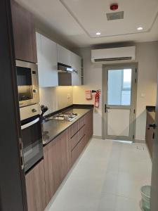 a kitchen with wooden cabinets and a stove top oven at Muscat City Stay-2BR Apt 108 near Grand & Avenue Mall in Ghubrah
