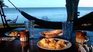a table with two plates of food and a view of the ocean at Hostel Los Chocoyos in Ometepe