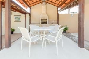 a dining room with a table and white chairs at Bela casa de praia sossegada no Centro de Búzios in Búzios