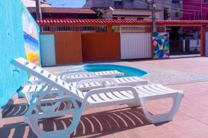 a pair of white benches sitting on a patio at Pousada mirante do Sol in Piúma