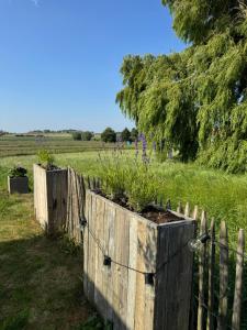 a wooden fence with a planter in a field at Koekeloeren in Hooglede