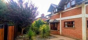 a brick house with a fence and some plants at Pichincha Bariloche DAT in San Carlos de Bariloche