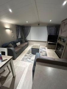 リルにあるLyons Robin Hood - 3 Bedroom Static Caravanのソファとテーブルのあるリビングルーム