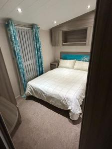 リルにあるLyons Robin Hood - 3 Bedroom Static Caravanのベッドルーム1室(青いヘッドボード付きのベッド1台付)