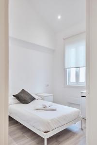 a white bedroom with a bed and a window at San vicente in A Coruña